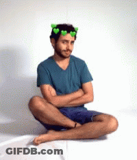 Man Sitting With Arms Crossed And Green Hearts Crown GIF