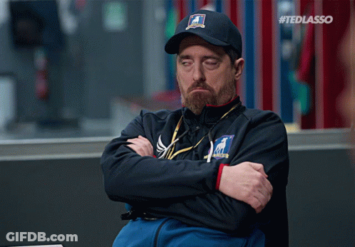 Man Sitting With Arms Crossed Wearing Ted Lasso Hat GIF