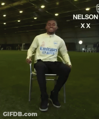 Man Sitting With Arms Outstretched In Emirates Fly Better Shirt GIF