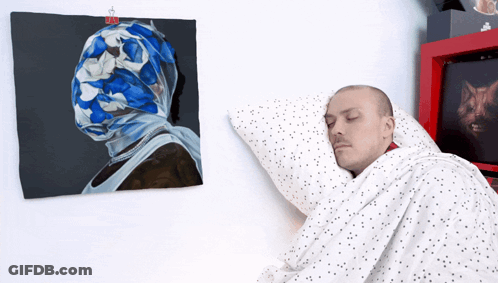 Man Sleeping Before Painting Of Man's Head GIF