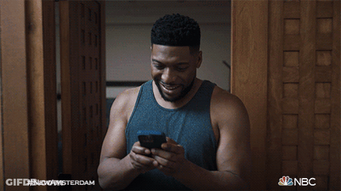 Man Smiling At Cell Phone With NBC Logo GIF