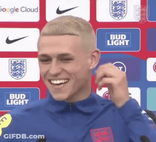 Man Smiling At Microphone In Front Of Bud Light Sign GIF