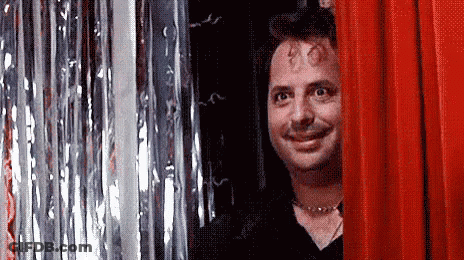 Man Smiling Behind Red Curtain GIF