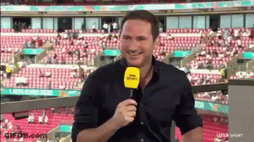 Man Smiling Holding Microphone In Stadium GIF