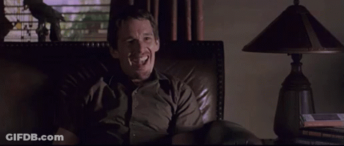 Man Smiling In Chair In Dark Room GIF