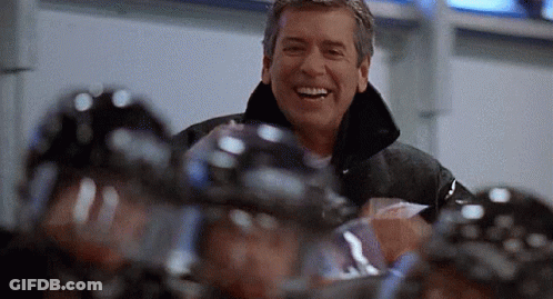 Man Smiling In Front Of Hockey Players GIF