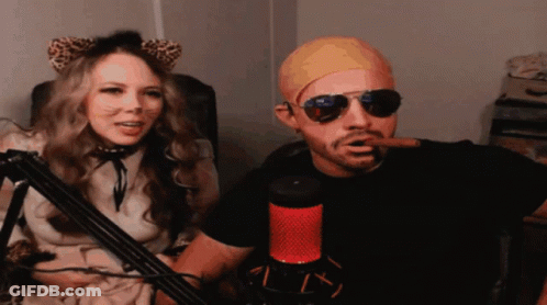 Man Smoking Cigar Next To Woman With Cat Ears And Sunglasses GIF