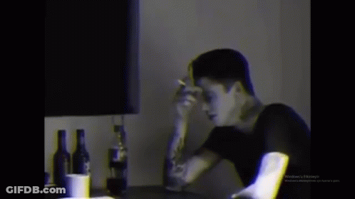 Man Smoking Cigarette At Table With Alcohol GIF