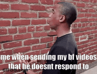 Man Smoking Cigarette Talking By Brick Wall GIF