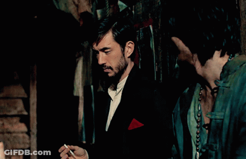 Man Smoking Cigarette With Red Pocket Square In Dark Room GIF