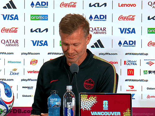 Man Speaking Into Microphone In Front Of Qatar Airways Ads GIF