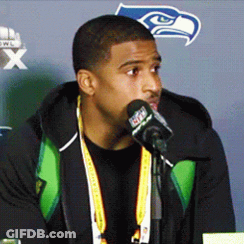 Man Speaking Into Microphone With Seahawks Logo GIF