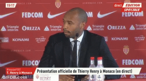 Man Speaks Into Microphone At Red Fedcom Backdrop GIF