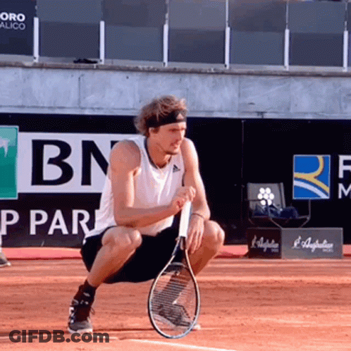 Man Squatting Holding Tennis Racquet Near BN Logo GIF