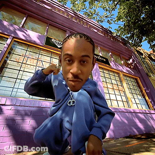 Man Squatting In Front Of Purple Building With Jewelers Sign GIF