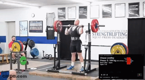 Man Squatting With Barbell In Front Of Strengthlifting Sign GIF