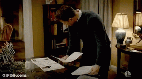 Man Standing At Desk Holding Papers GIF