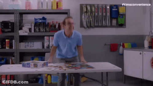 Man Standing At Table With Puzzle Box GIF