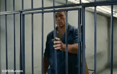 Man Standing Behind Bars In Jail Cell GIF