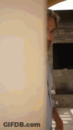 Man Standing Behind Wall In Living Room GIF