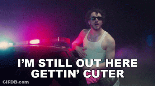 Man Standing By Police Car Saying I'm Still Out Here Gettin' Cuter GIF