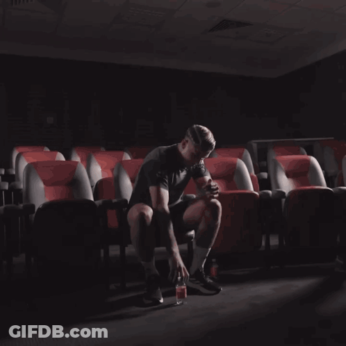 Man Standing In Auditorium Holding Bottle GIF