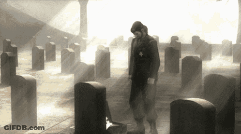 Man Standing In Cemetery With Cross On Chest GIF