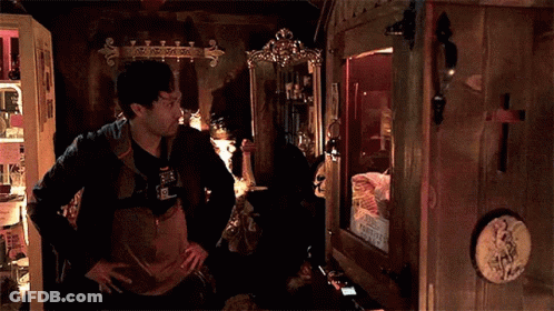 Man Standing In Dark Room Looking At Mirror GIF