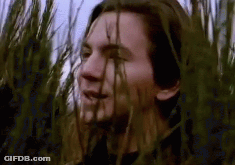 Man Standing In Field Of Tall Grass Looking At Camera GIF