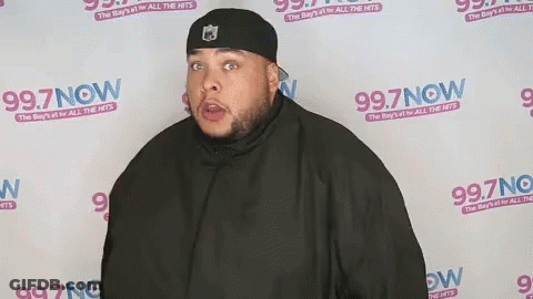 Man Standing In Front Of 99.7 Now Wall GIF