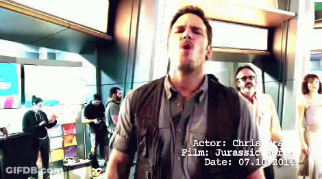 Man Standing In Front Of Actor Chris Rea Jurassic World Sign GIF