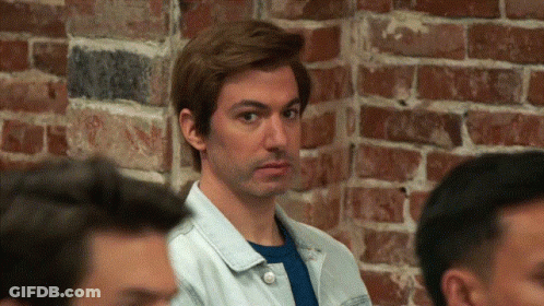 Man Standing In Front Of Brick Wall Looking At Camera GIF