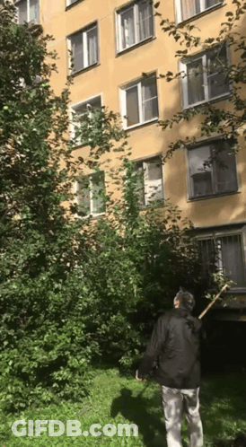Man Standing In Front Of Building With Rake GIF