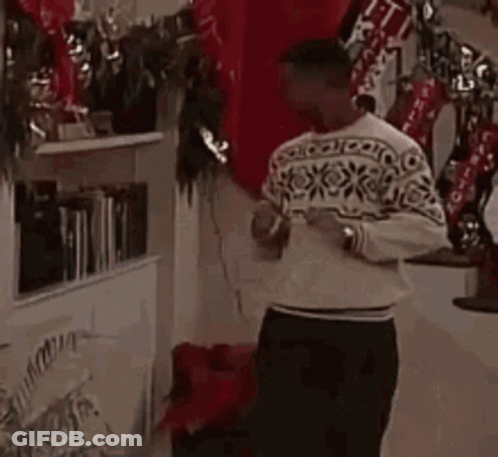 Man Standing In Front Of Christmas Tree Wearing Sweater GIF