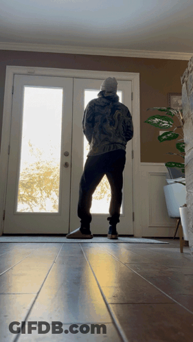 Man Standing In Front Of Door With Plant GIF