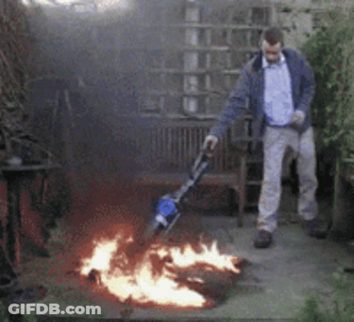 Man Standing In Front Of Fire With Vacuum GIF