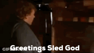 Man Standing In Front Of Fireplace Saying Greetings Sled God GIF