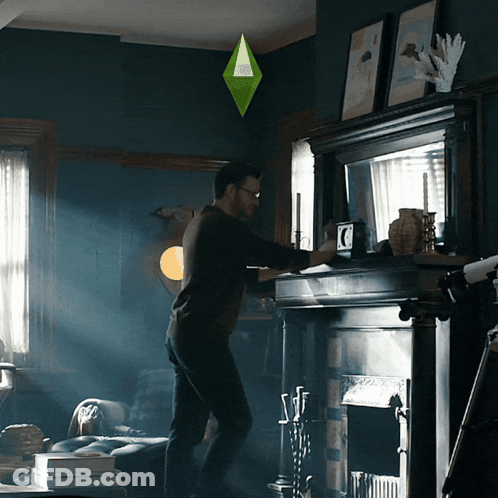 Man Standing In Front Of Fireplace With Green Diamond Hanging Above GIF