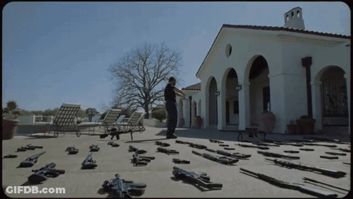 Man Standing In Front Of House With Guns GIF