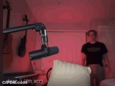 Man Standing In Front Of Microphone In Dark Room GIF
