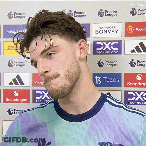 Man Standing In Front Of Premier League Ads GIF