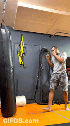 Man Standing In Front Of Punching Bag GIF