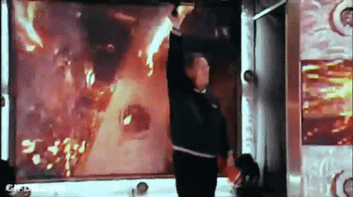 Man Standing In Front Of Screen With Flames GIF