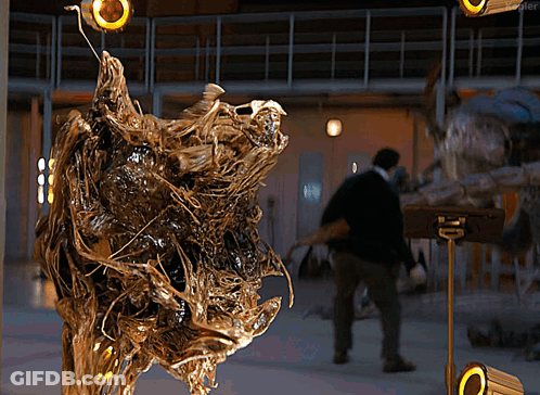 Man Standing In Front Of Sculpture With Blurred Person Behind GIF