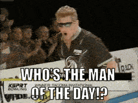 Man Standing In Front Of Sign Saying Who's The Man Of The Day GIF