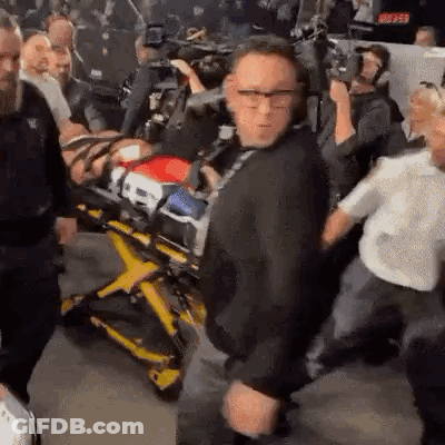 Man Standing In Front Of Stretcher With Man On It GIF