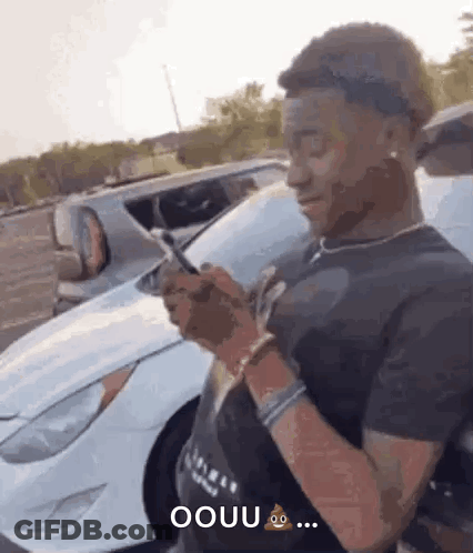 Man Standing In Front Of White Car With Cell Phone GIF