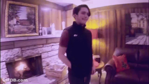 Man Standing In Living Room In Front Of Fireplace And Couch GIF