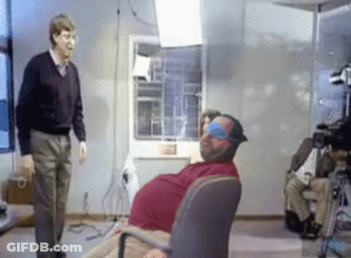 Man Standing Next To Blindfolded Man In Chair GIF