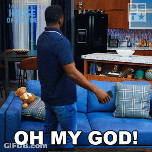 Man Standing Next To Blue Couch Saying Oh My God GIF